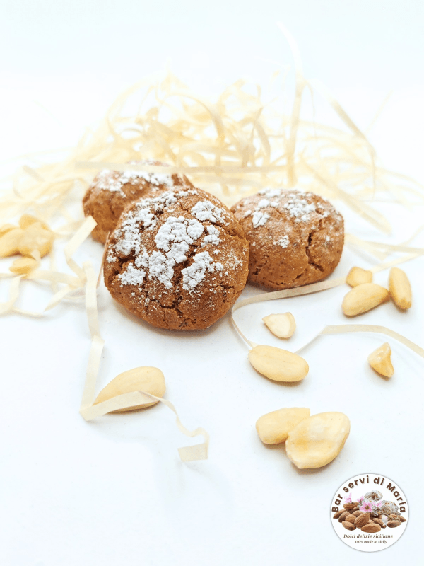 Tre biscotti amaretto alle mandorle dolci delizie siciliane su letto di pagliuzza e mandorle pelate attorno